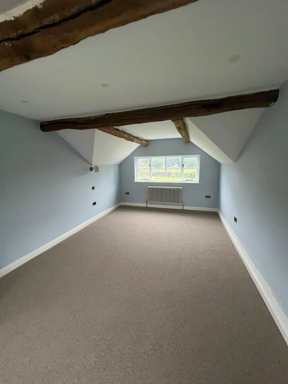 Blue-painted room with exposed timber ceiling beams and a white ceiling