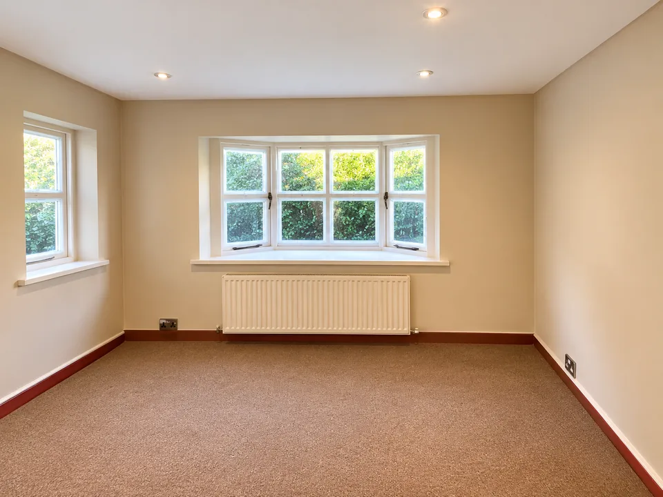 Neutral-painted room with a bay window, white ceiling and timber-coloured skirting boards